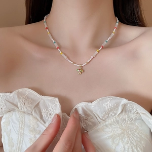 Detail of beaded dopamine style necklace with a colorful metallic mushroom pendant for women