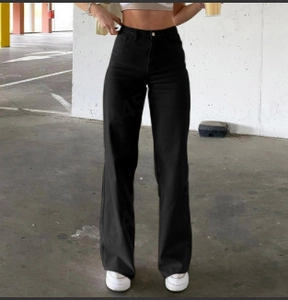 Detail shot of high-waisted black wide-leg trousers in an industrial setting