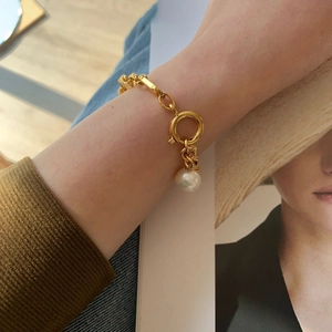 Vue détaillée du bracelet à chaîne plaqué or 18 carats avec perle porté sur le poignet