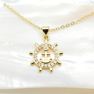Detailed macro view of 18k gold-plated nautical pendant with helm and anchor motifs