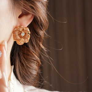 Détail de boucle d'oreille fleur vintage avec émail camel et cristal sur le mannequin