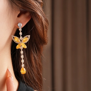 Close-up of model wearing gold tassel earrings with zircon butterfly and water drop pendant