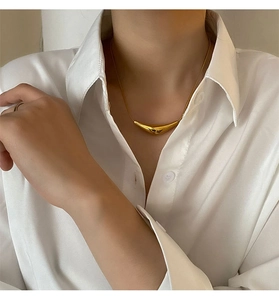 Gros plan d'un collier avec pendentif croissant doré sur femme en chemise de coton blanc