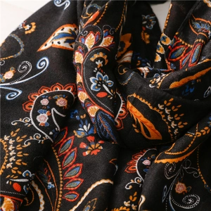 Close-up of intricate paisley pattern on soft black fabric scarf with fabric texture