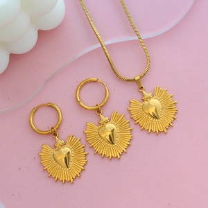 Parure de bijoux cœur sacré doré avec collier et boucles d'oreilles sur fond rose