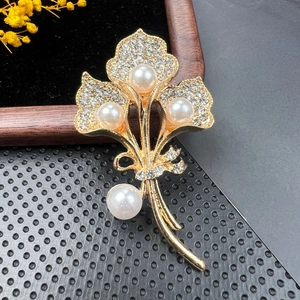 Close-up of golden brooch with elegant pearls and sparkling crystals on black velvet