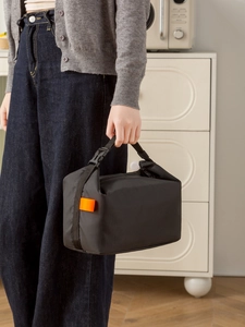 Detail of insulated lunch bag with orange label and adjustable buckle handle strap