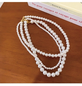 Detail of elegant three-layer pearl necklace with gold clasp on vintage book background