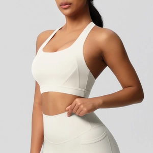 Detail van de high-waist yoga legging met zijzakken en textuur van de sportbeha in crème