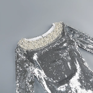 Detail of silver sequin evening gown showing pearl neckline and intricate embroidery