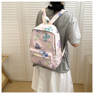 Detailed back view of pink butterfly print school backpack worn by model in room