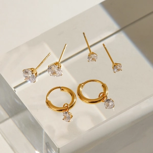 Vue macro détaillée de trois paires de boucles d'oreilles en acier doré avec des zircons