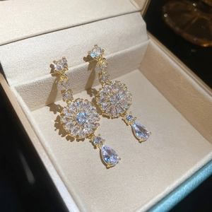 Detailansicht goldener Ohrhänger mit Zirkonia-Blumen und funkelnden Wassertropfen