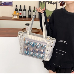 Detail of silver tote bag with clear window, anime badges and side ribbon drawstring