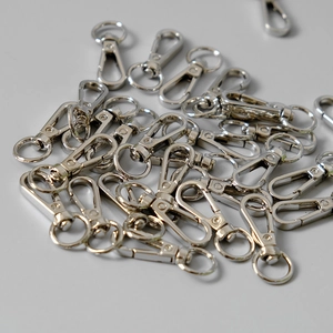 Pile of silver metal lobster claw clasps with 360-degree swivel rings for bags