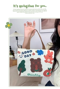 Close-up of a white canvas tote bag with cartoon bear and rabbit prints with metal snap button