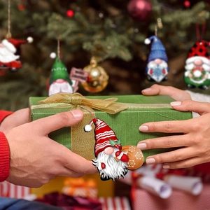 Close-up of festive wooden Christmas gnome gift tag tied to a green box with jute rope
