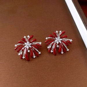 Detailed view of red fireworks-shaped zircon stud earrings on dark textured background
