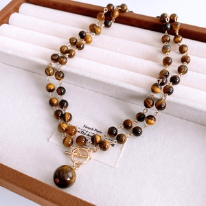 Detail of double-layer tiger eye stone necklace with gold toggle clasp on velvet display box