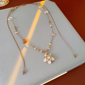 Détail d'un pendentif étoile ethnique fait main avec tissage brun et perles de mode