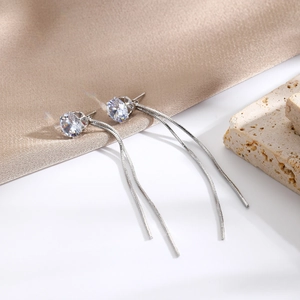 Macro shot of silver tassel earrings with round cubic zirconia and delicate snake chains
