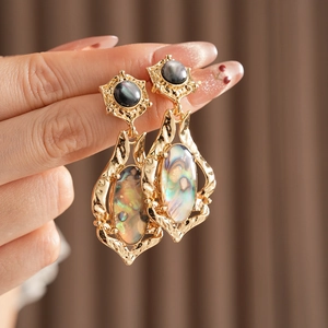 Détail de boucles d'oreilles vintage en or avec nacre ovale et pierres noires