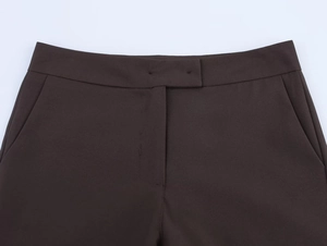Detailed close-up of high-waist dark brown suit pants with button and side pockets