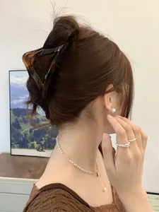 Detail of tortoise shell claw clip with gold pearl necklace and ring set