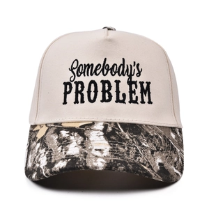 Detail of Somebody's Problem embroidery on a beige trucker hat with camo brim