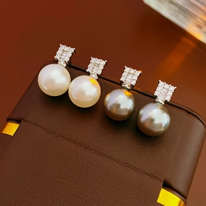Macro shot of silver pearl earrings with white and gray pearls and pavé zircons
