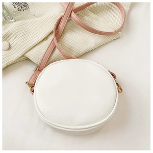 Detail of a mini round kids purse with white PU leather and pink shoulder strap