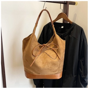 Detailed view of camel faux suede tote bag with decorative bow and leather trim