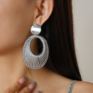 Close-up of silver velvet woven hollow hoop earring worn by a model in soft lighting