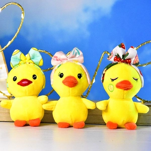 Close-up detail of three cute yellow plush duck toys wearing colorful bow headbands