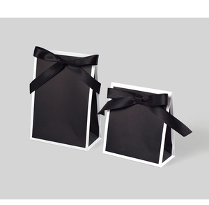 Vue détaillée des sacs cadeaux noirs minimalistes avec bords blancs et nœuds en satin