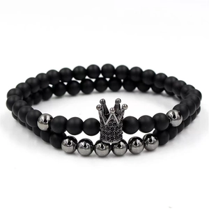 Close-up of matte black beads bracelet with gunmetal accents and a diamond crown charm