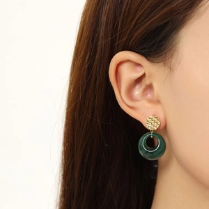 Detail of dark green resin earrings with hammered gold metal texture on female model