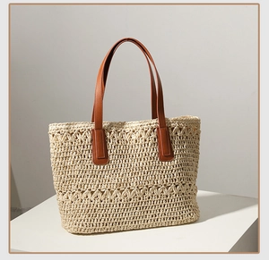 Detail of hand-woven straw tote bag with brown leather straps and intricate patterns