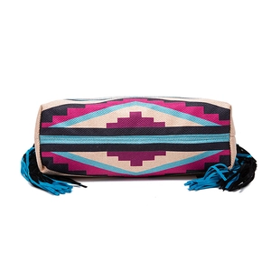 Detail of woven bohemian clutch with colorful geometric patterns and long side tassels