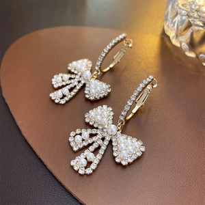 Dettaglio macro di orecchini a fiocco eleganti con strass e perle luccicanti