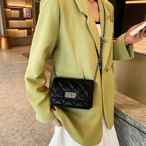 Chic black quilted chain crossbody bag with metal lock shown on a model in green blazer