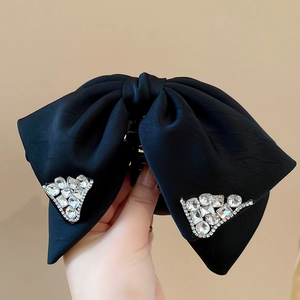 Detail of a large black satin bow hair claw clip with sparkling rhinestone triangle accents