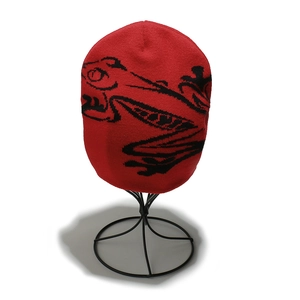 Detail of red knit beanie featuring black jacquard frog pattern and premium texture