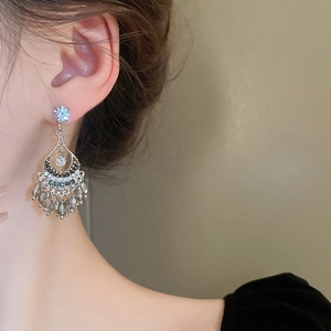 Close-up of bohemian fan-shaped earrings with crystal tassels and sparkling rhinestones