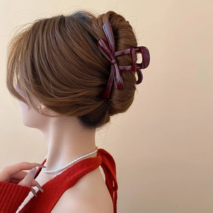 Rear view of wine red resin bow hair claw clip securing a ponytail on a model
