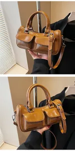 Detail view of retro brown saddle bag with double front pockets and cylindrical handles