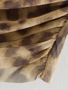 Detail of sheer leopard print mesh fabric with elegant layered pleats and textures