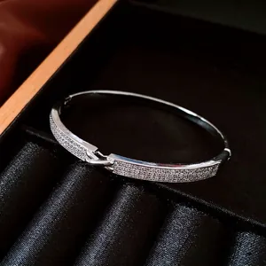 Bracelet jon jonc plaqué or 18 carats avec fermoir entrelacé et zircons brillants