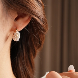 Detail of French style gold earrings with pearls and crystals worn by a model
