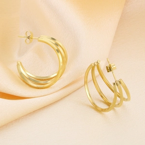 Dettaglio degli orecchini a triplo strato a forma di C in oro su elegante seta rosa